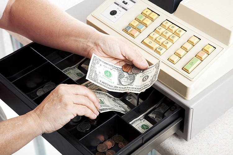 Teller Removing Cash from a Cash Register Representing Specialty Retailers Cash Management